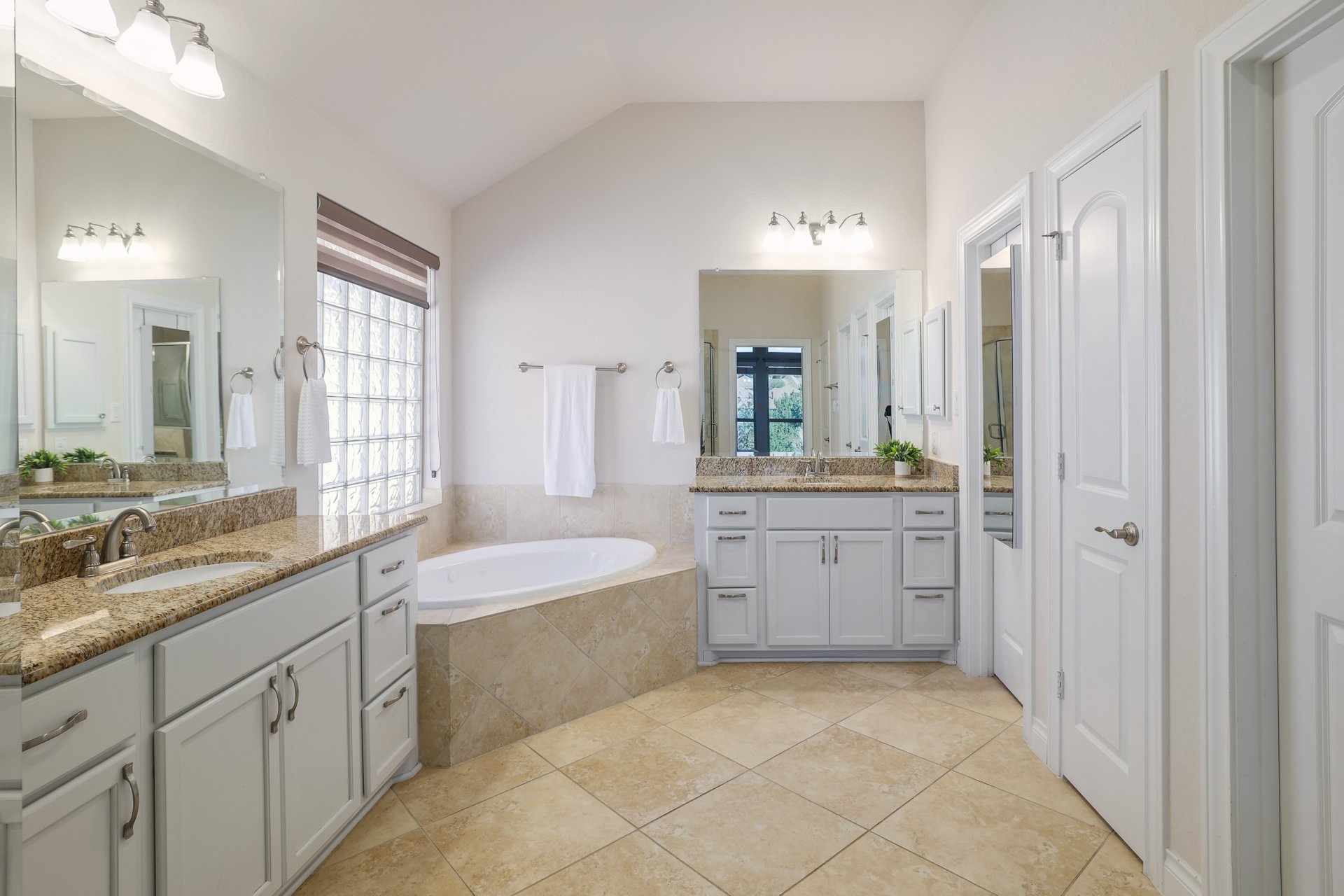 173 Santa Maria Street Georgetown, TX 78628 - Photo 23 of 39 Bathroom featuring a built-in corner soaking tub, dual vanities with granite countertops, light-colored cabinetry, and large format tiled flooring