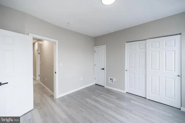 an empty room with wooden floor and closet area