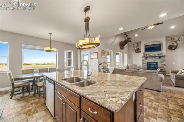 a kitchen with granite countertop a stove a sink a oven dining table chairs and chandelier