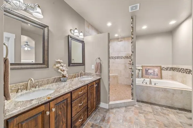a spacious bathroom with a granite countertop double vanity sink a mirror and a bathtub