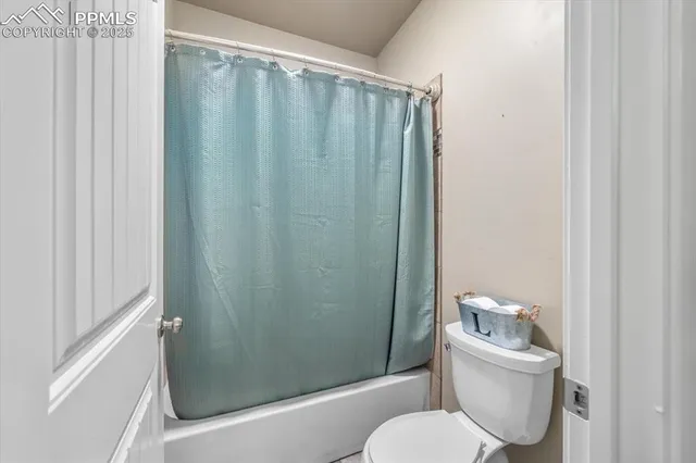 a bathroom with a toilet and a shower curtain