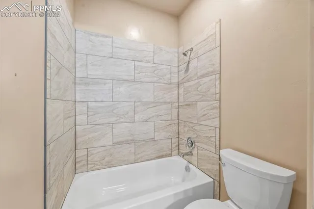 an empty room with a chandelier fan and windows