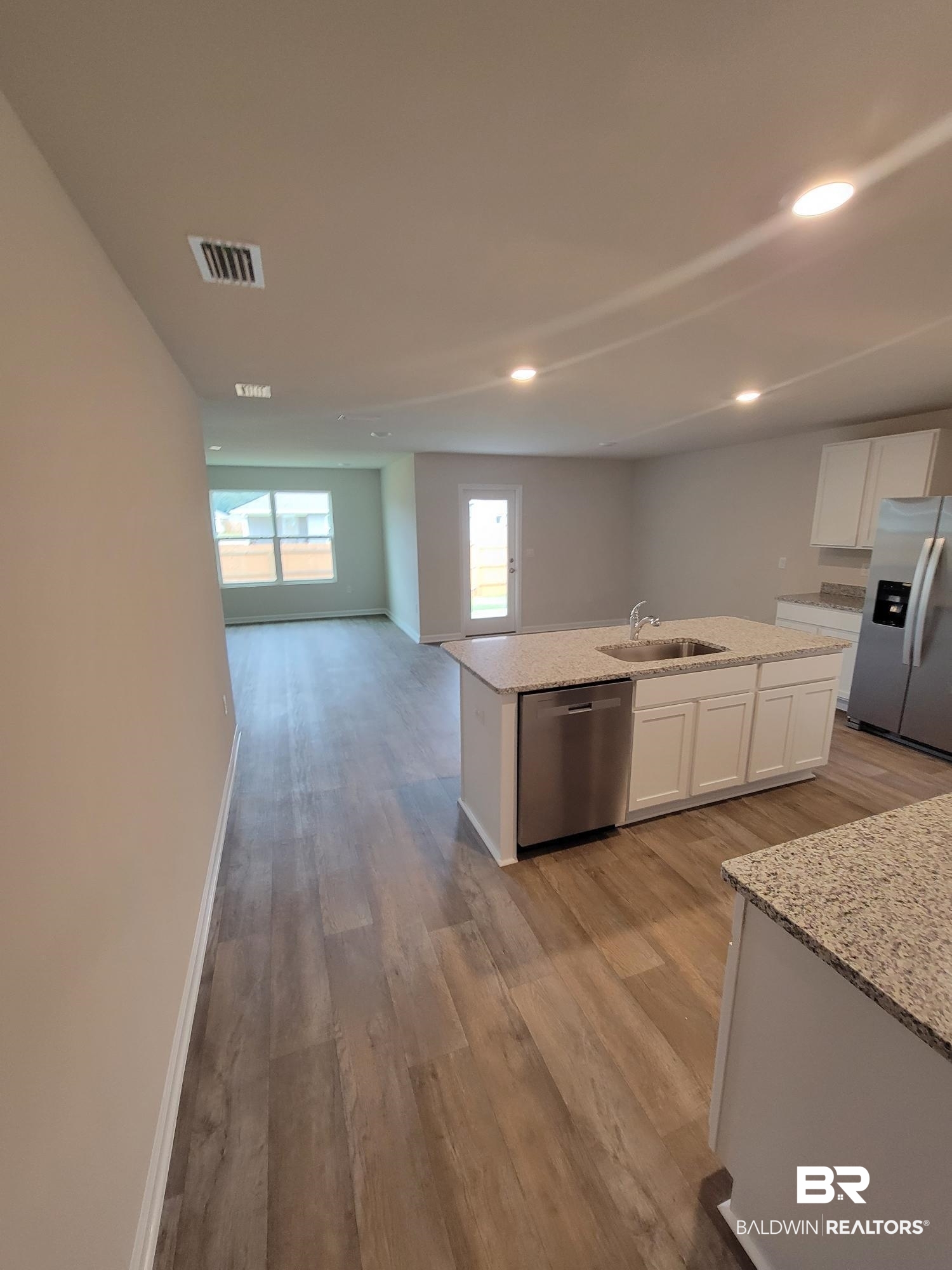 24625 Ponder Loop Loxley, AL 36551 - Photo 10 of 30 Kitchen featuring white cabinetry, appliances with stainless steel finishes, sink, light hardwood / wood-style floors, and a kitchen island with sink