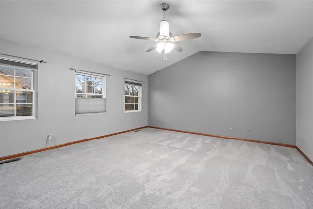 an empty room with windows and chandelier fan