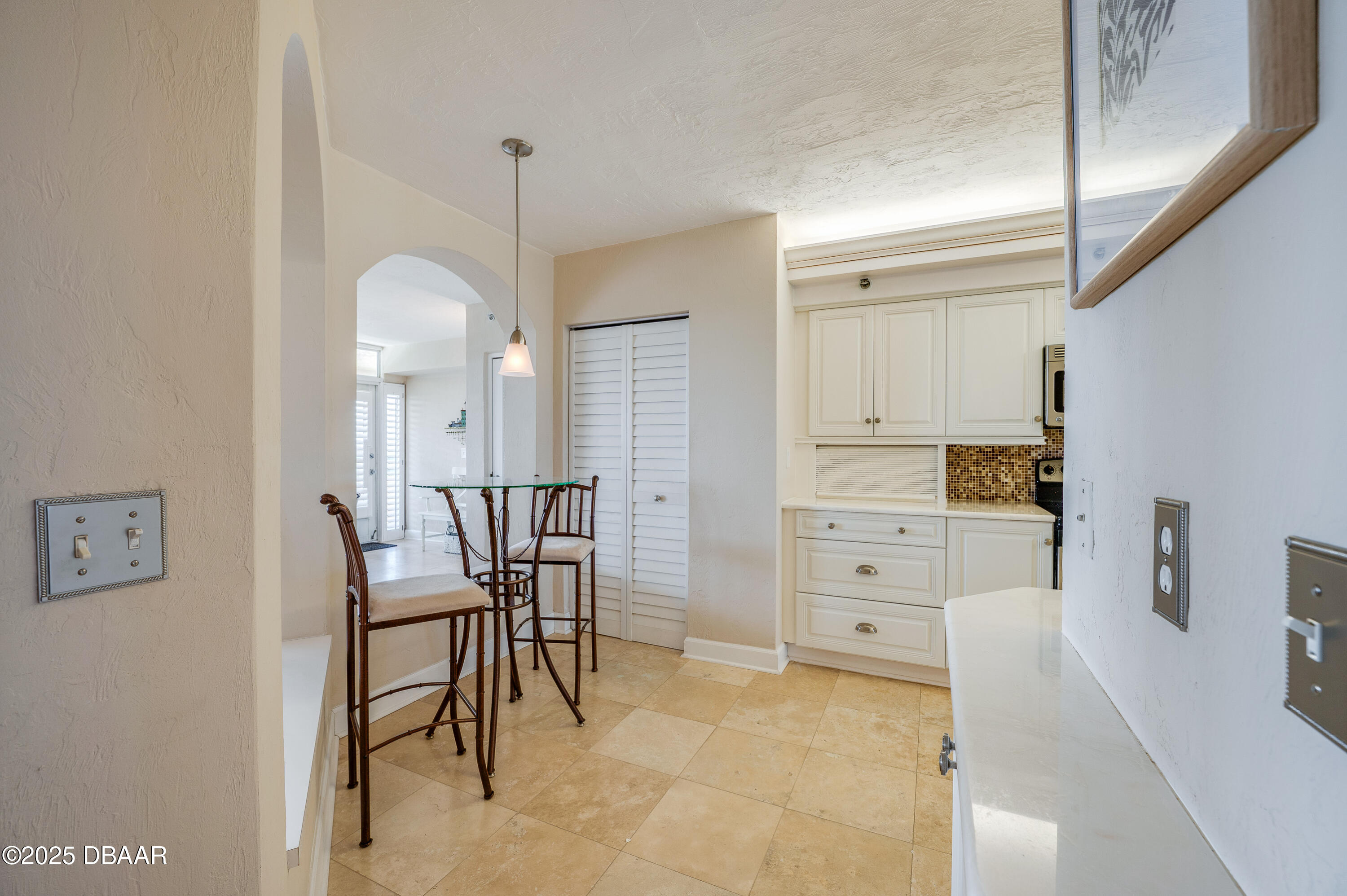 4525 South Atlantic Avenue, Unit 1704 Ponce Inlet, FL 32127 - Photo 11 of 45 a kitchen with white cabinets and chairs