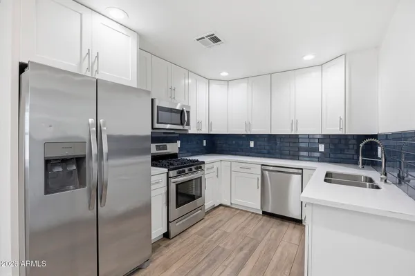 a kitchen with stainless steel appliances granite countertop a refrigerator sink and stove