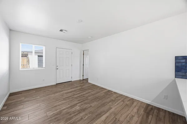 a view of an empty room with wooden floor and a window