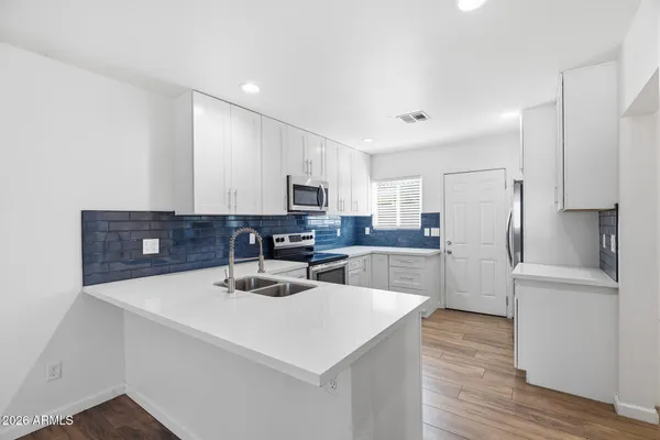 a kitchen with a refrigerator a stove top oven a sink cabinets and wooden floor