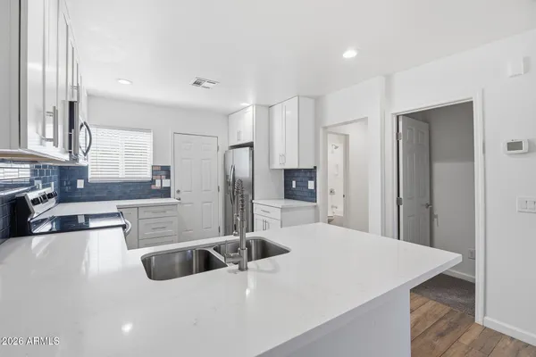 a large kitchen with stainless steel appliances a large counter top a refrigerator and a sink