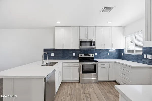a kitchen with a sink white cabinets and white appliances