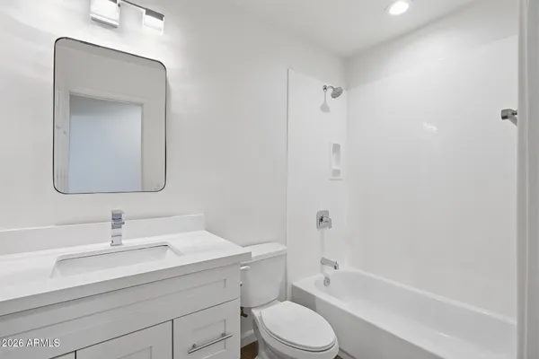 a bathroom with a toilet a sink a mirror a bathtub and vanity