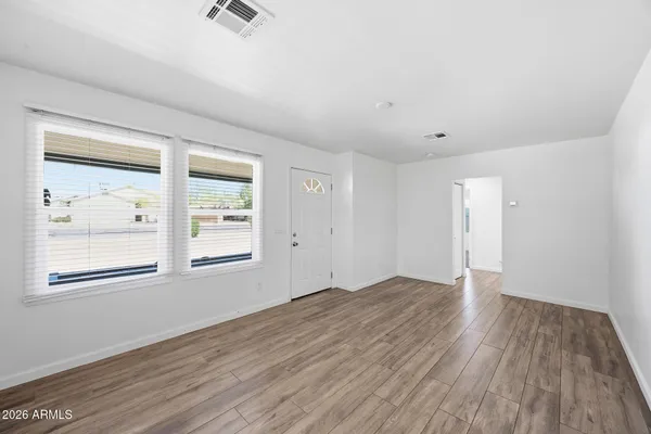 an empty room with wooden floor and windows