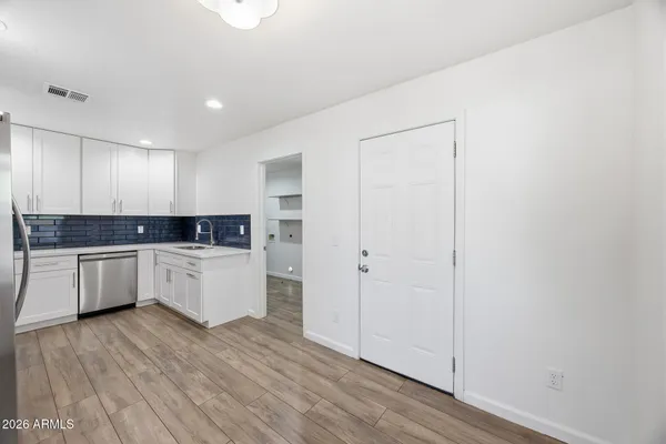 a large white kitchen with a refrigerator a sink dishwasher a stove and white cabinets with wooden floor