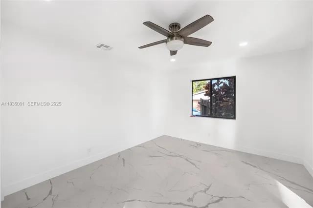 an empty room with windows and fan