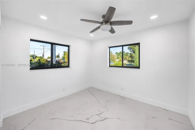 an empty room with ceiling fan and window