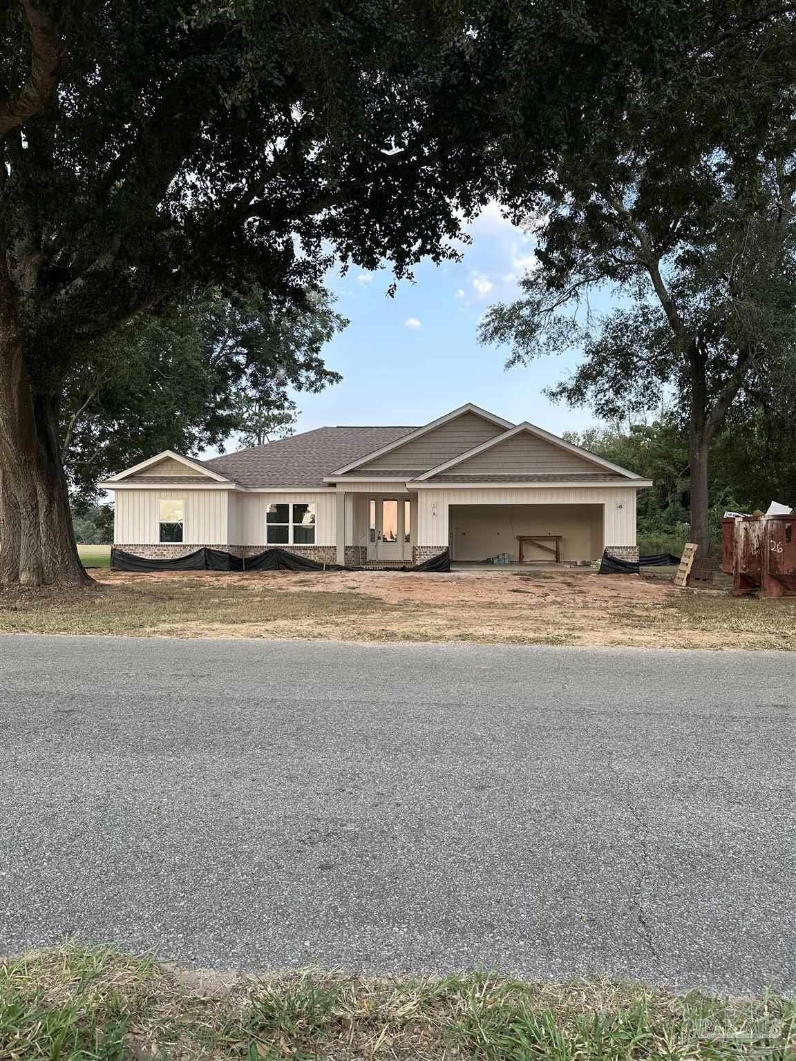 a front view of a house with a garden and trees