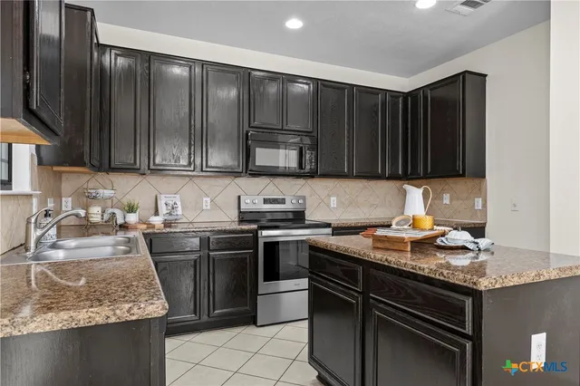 a kitchen with kitchen island granite countertop stainless steel appliances a stove sink and cabinets