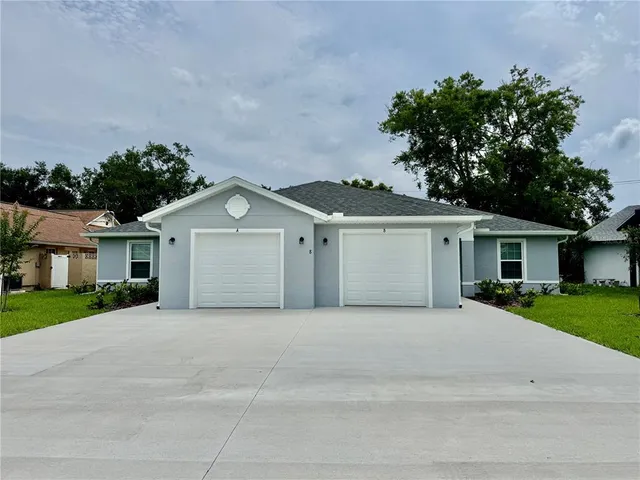 a front view of a house with a garden and trees