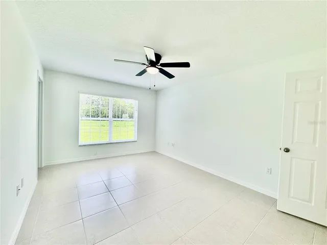 an empty room with a ceiling fan and a window