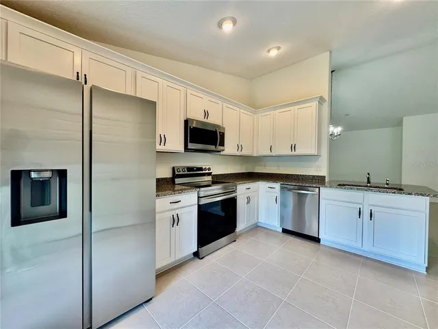 a kitchen with granite countertop white cabinets and stainless steel appliances