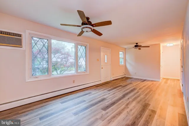 a view of empty room with wooden floor and fan
