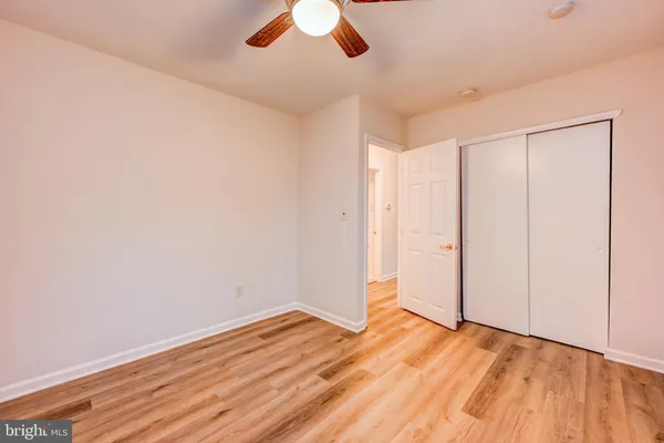 an empty room with wooden floor cabinet and windows