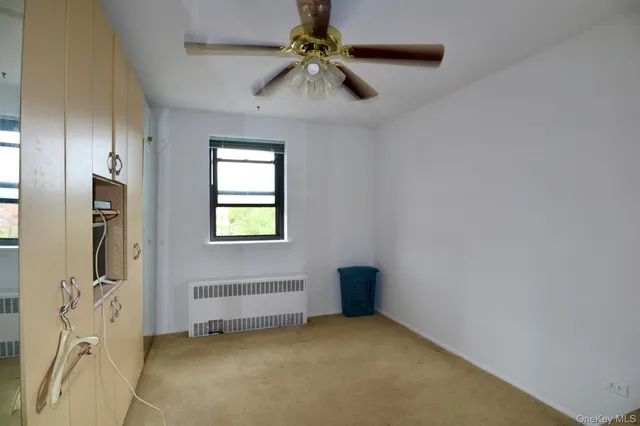 a view of an empty room with window and chandelier fan