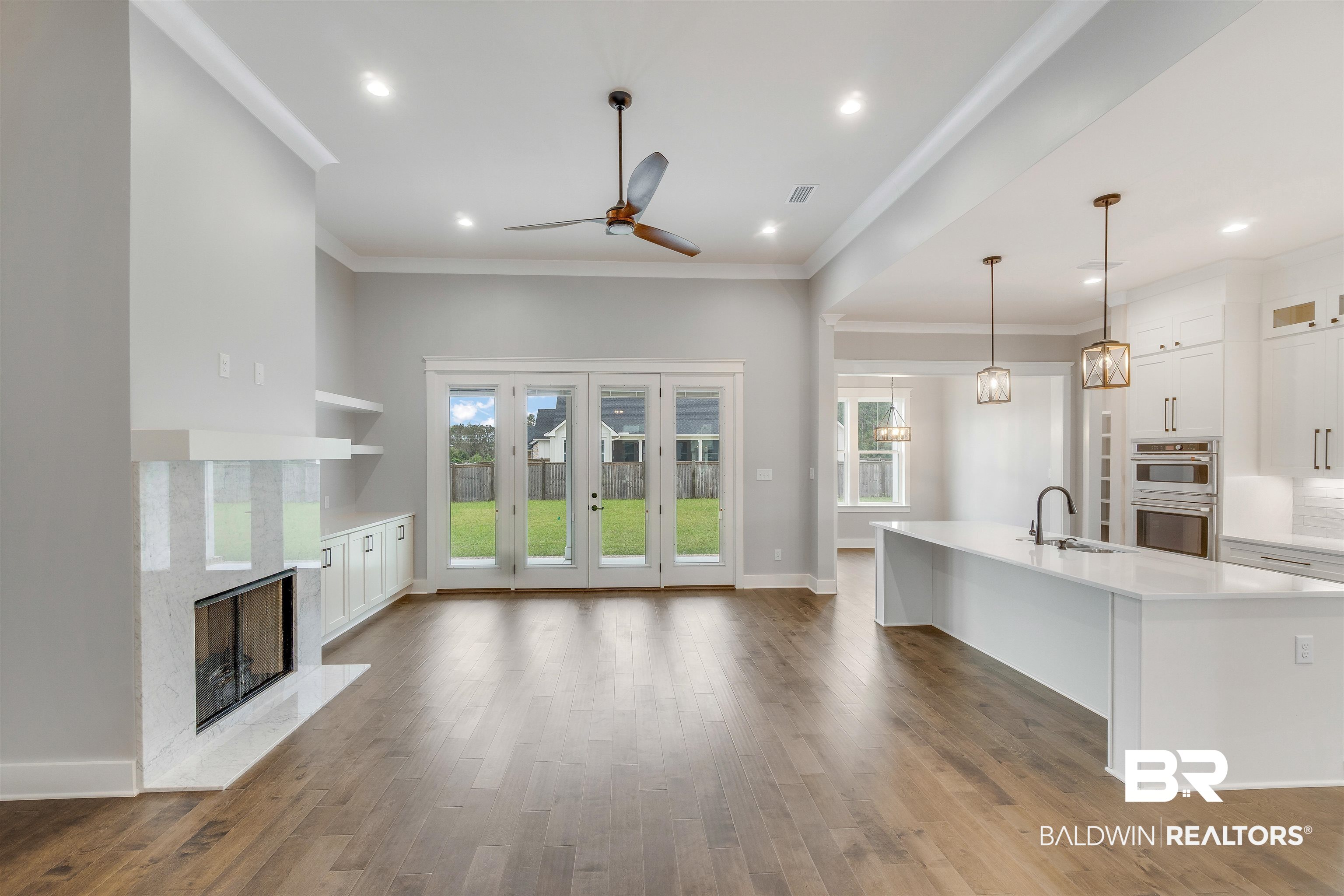 10985 Atrium Avenue Fairhope, AL 36532 - Photo 8 of 58 Kitchen featuring white cabinets, light wood-type flooring, light stone counters, a center island with sink, and pendant lighting
