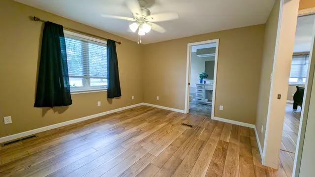 a view of an empty room with wooden floor and a window