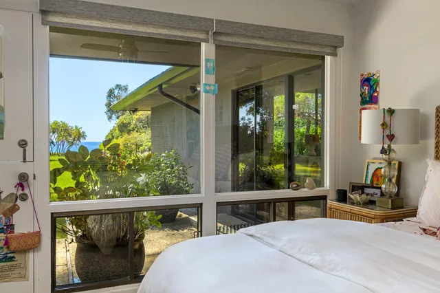 a bedroom with a bed and a large window with the outer view