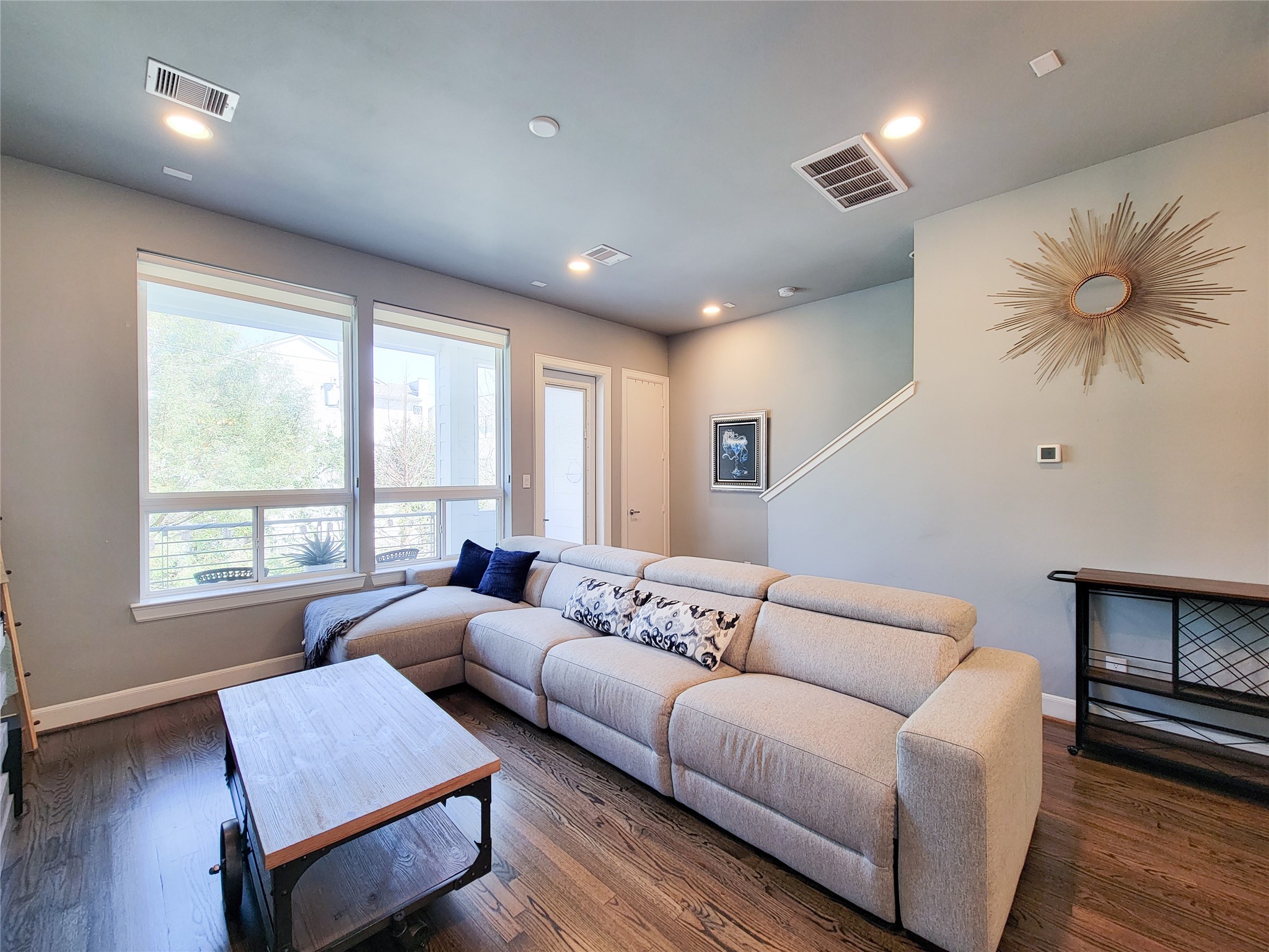 1705 Eado Point Lane Houston, TX 77003 - Photo 15 of 50 Bright, cozy living room with large windows, modern lighting, and hardwood floors. Features a comfortable sectional sofa, stylish wall decor, and access to a staircase.