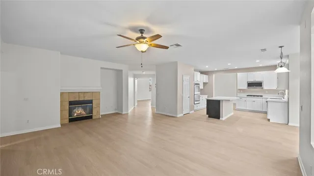 a view of an empty room with a kitchen and a fireplace