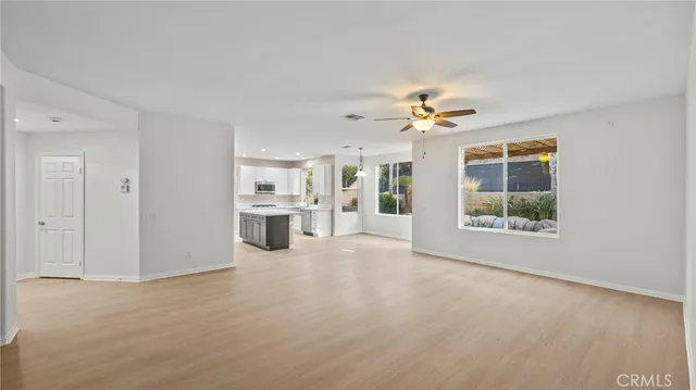 an empty room with chandelier fan and windows