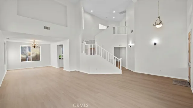 a view of an empty room with wooden floor and a kitchen