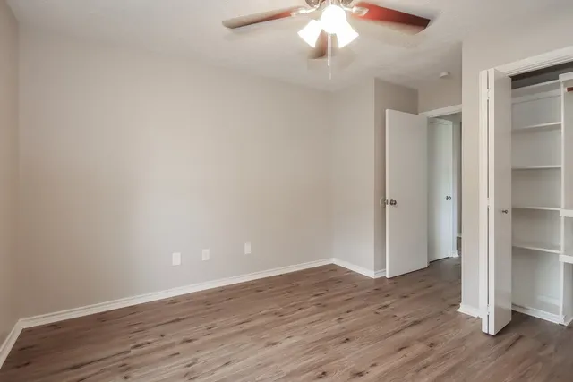 an empty room with wooden floor and chandelier fan
