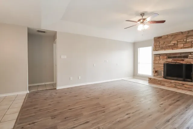 a view of empty room with wooden floor and fireplace
