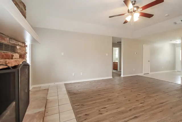 a view of an empty room with window and chandelier fan