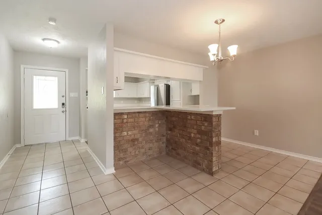 an empty room with kitchen view and fireplace