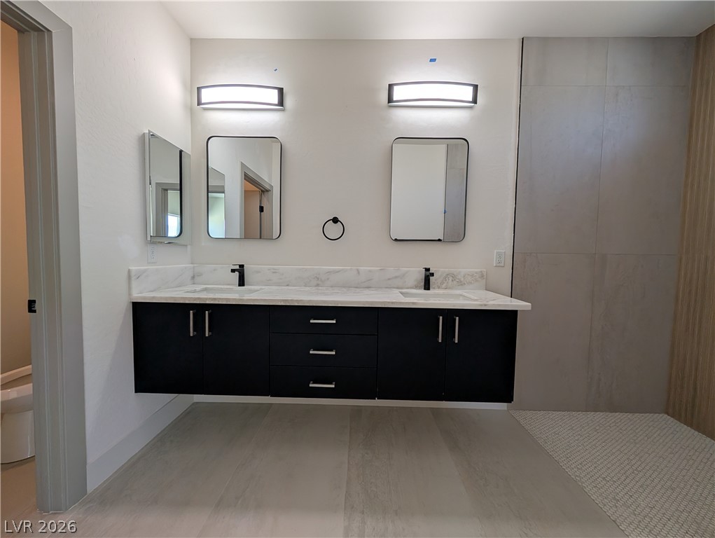 4670 Medicine Man Road Pahrump, NV 89048 - Photo 17 of 36 Dual vanities with sleek black cabinetry and marble countertops enhance this modern primary bathroom.