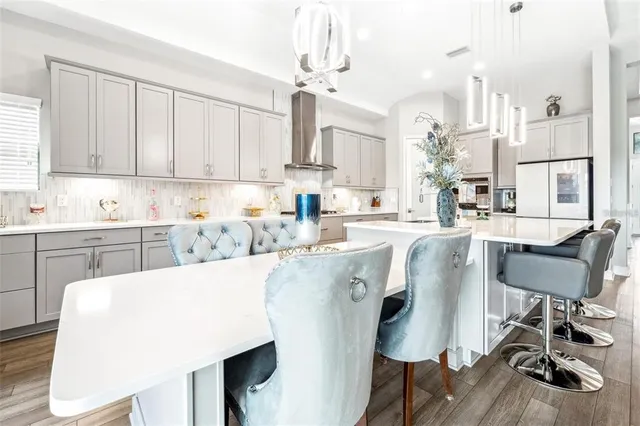 a living room with stainless steel appliances furniture a rug and a kitchen view