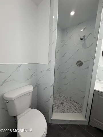 a white toilet sitting next to a shower