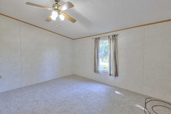an empty room with windows and fan