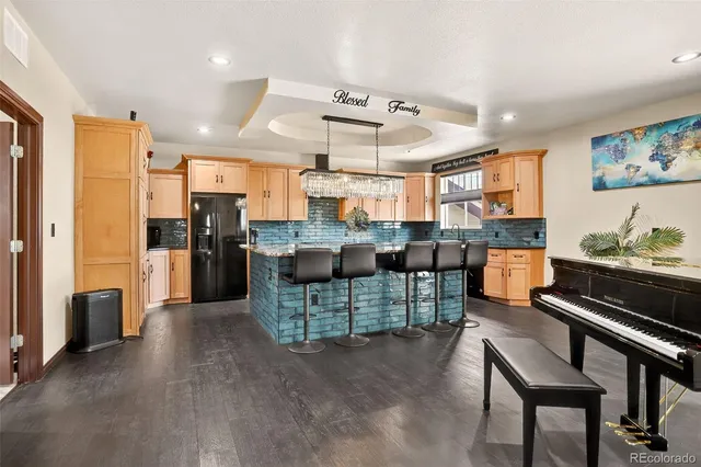 a open kitchen with stainless steel appliances kitchen island granite countertop a refrigerator a stove and a sink with couches