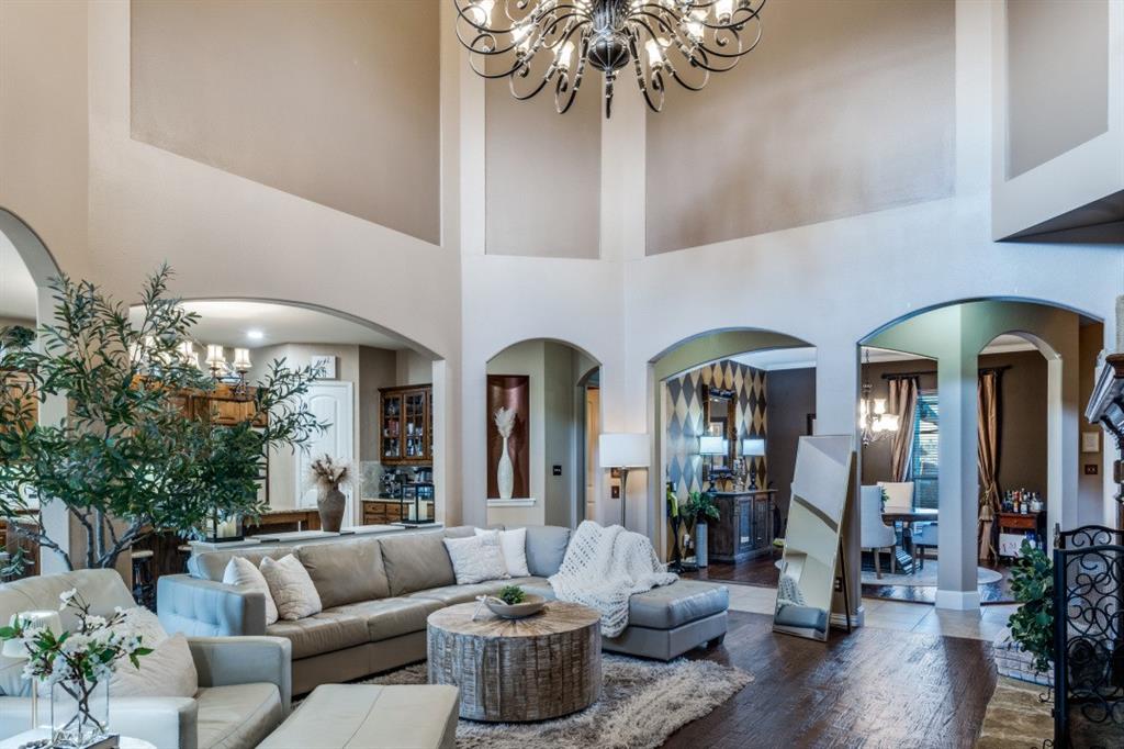 2810 Baker Street Sachse, TX 75048 - Photo 5 of 26 Living room featuring a chandelier, a high ceiling, arched walkways, and hardwood / wood-style flooring