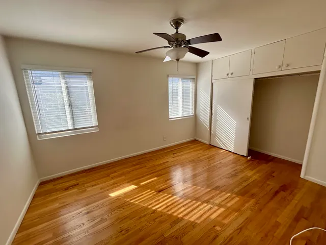 a view of empty room with wooden floor and fan
