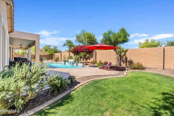 a view of a yard with a table and chairs under an umbrella