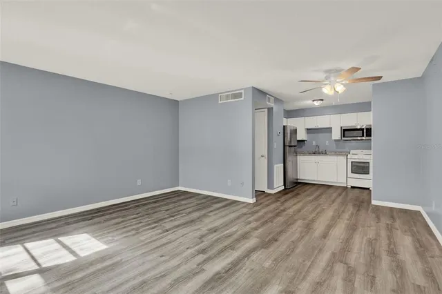a view of a kitchen with wooden floor and a ceiling fan