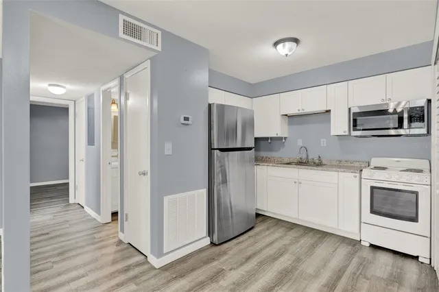 a kitchen with granite countertop a refrigerator stove and sink