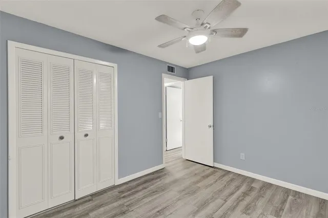 an empty room with wooden floor and ceiling fan
