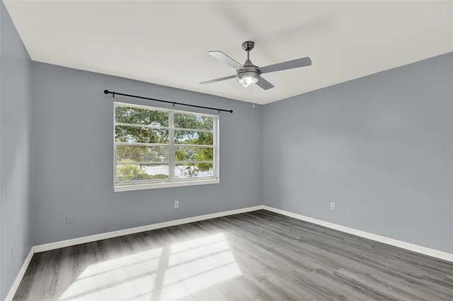 a view of empty room with wooden floor and fan